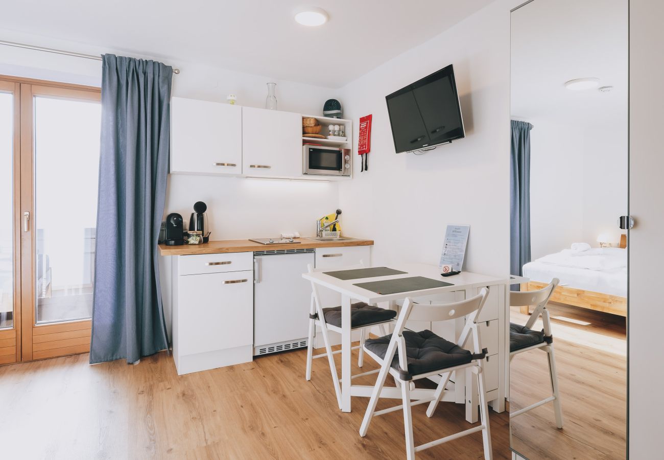 Dining room in Haus Altenberger Apartments by we rent, with a table, chairs, and a kitchen with a stove, oven.