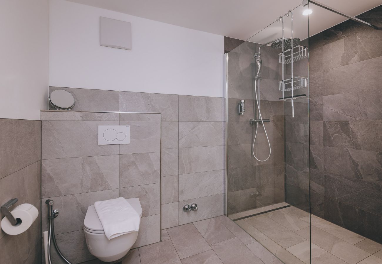 Bathroom in Haus Altenberger Apartments by we rent. Modern shower with double sink, toilet, and towel.