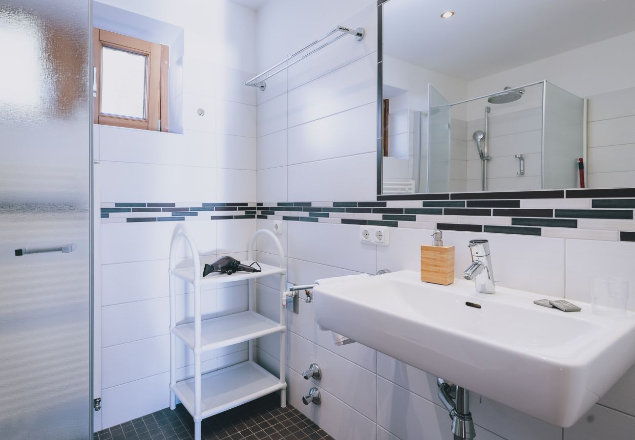 Badezimmer im Apartments Haus Altenberger by we rent. Waschbecken, Seife und Spiegel. Moderne Badaustattung. 