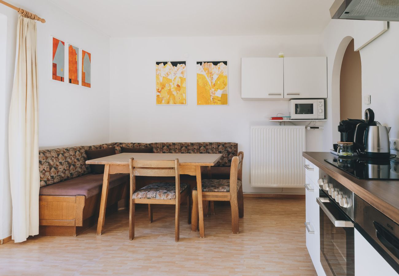 Wohnbereich in der Ferienwohnung Apartments Haus Altenberger by we rent. Esstisch, Küche mit Herd, Ofen.